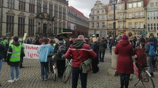 Menschen stehen mit Bannern auf dem Bremer Marktplatz.