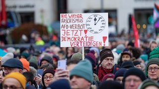 Auf einer Demonstration gegen die AfD ist das Plakat zu lesen: "Nie wieder Faschismus-AfD-Verbot. Jetzt Demokratie verteidigen!" Eine Uhr zeigt auf 5 nach 12.