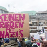 Ein Mensch hält ein Schild in die Höhe, auf dem steht: "Keinen Frieden mit Nazis"