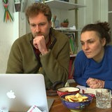 Ein Mann mit Bart und eine dunkelhaarige Frau schauen auf ein MacBook.