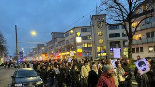 Demonstranten laufen eine Straße in Bremen entlang. Sie gedenken den Opfern des rassistischen Anschlags in Hanau vor vier Jahren.