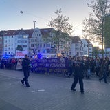 Menschen laufen während einer Demonstration über eine Straße in der Bremer Neustadt. Im Vordergrund sind Polizisten zu sehen.