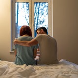 Ein Mann sitzt tröstend neben einer Frau auf dem Bett (Symbolbild)