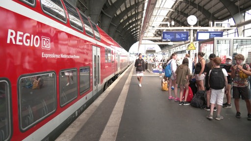Ein Zug der Deutschen Bahn und einige Menschen am Gleis im Bremer Hauptbahnhof.