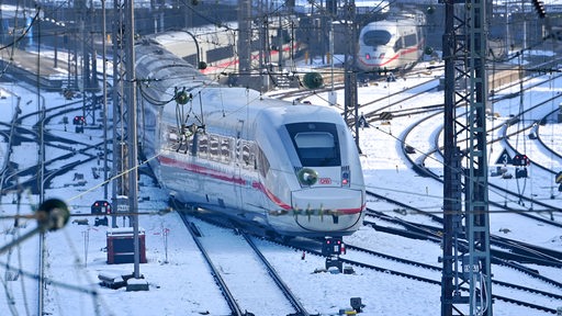 Ein Zug der DB steht auf Schienen im Schnee neben leeren Gleisen am Hauptbahnhof München