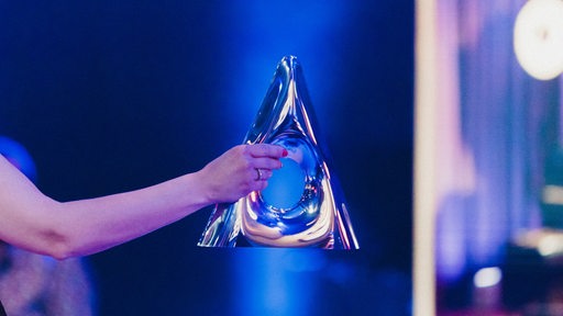 Eine Frau hält die Trophäe des Deutscher Jazzpreises