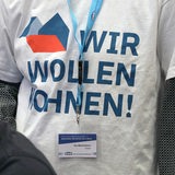 Eine Teilnehmerin der Versammlung steht mit einem T-Shirt mit der Aufschrift "Wir wollen Wohnen" auf der Jahrestagung des Deutschen Mieterbundes im Plenum.