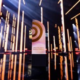 Auf einer Bühne steht eine Trophäe mit der Aufschrift "Deutscher Radiopreis".