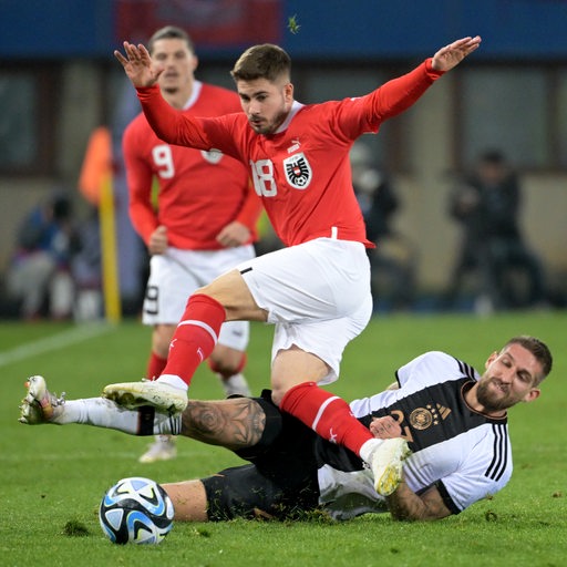 Österreich-Spieler Romano Schmid springt über seinen DFB-Gegenspieler Robert Andrich.