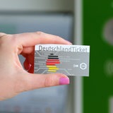 Eine Hand hält ein Deutschlandticket.