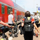 Fahrgäste laufen auf einem Bahnsteig neben einem Regionalexpress (Archivbild)