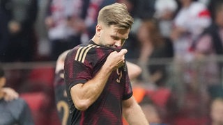 Stürmer Niclas Füllkrug zieht enttäuscht nach dem verlorenen Testspiel gegen Polen sein Nationaltrikot vors Gesicht.