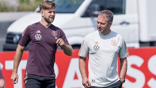 DFB-Stürmer Niclas Füllkrug und Bundestrainer Hansi Flick sprechen in einer Trainingseinheit miteinander.