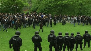 Polizisten begleiten Dutzende Fußballfans auf einer Wiese.