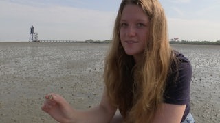 Diana Könemann bei ihrem Bundesfreiwilligendienst im Wattenmeer vor Dorum. Sie hält eine Muschel in der Hand.