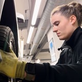 Eine junge Frau setzt einen Reifen an ein Auto