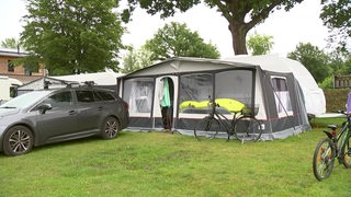 Ein Auto mit großen Camping-Zelt auf einem Camping Platz.