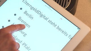 Ein Finger, welches auf ein Tablet Display zeigt, wo Bremen steht. 