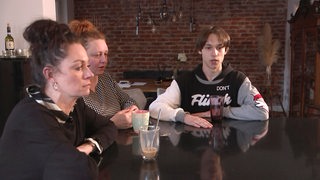 Uta Albanese sitzt mit Dimitri Kalistov und dessen Mutter am Tisch, nachdem die beiden aus der Ukraine geflohen sind.