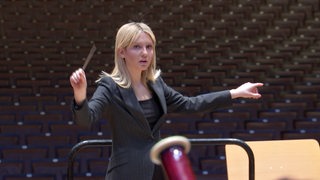 Zu sehen ist die Dirigentin Vanessa Benelli Mosell, während des Dirigierens.