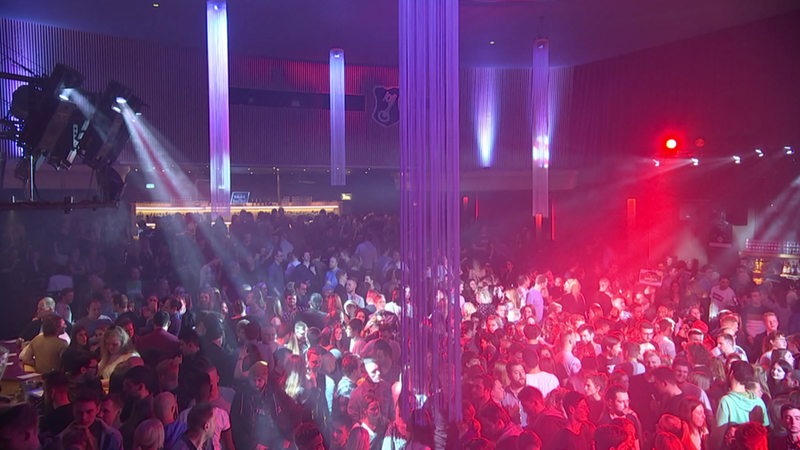 Eine Tanzfläche eines Clubs mit vielen Menschen und bunter Beleuchtung.