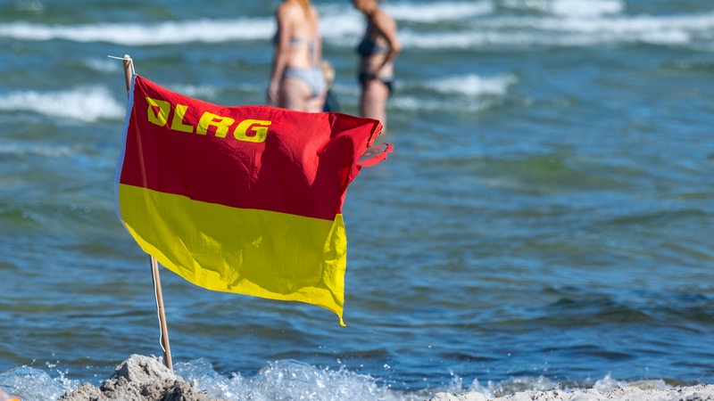 DLRG-Flagge weht am Strand vor dem Meer