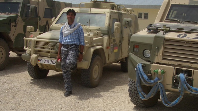 afghanischer Dolmetscher steht vor einem Jeep der Bundespolizei