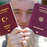 Ein türkischer und eine deutscher Reisepass werden von einem Mann in die Kamera gehalten.