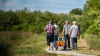 Vier Männer mit Bollerwagen