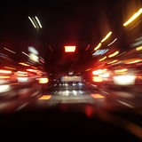 Bewegungsunscharf fotografierte Autos von hinten mit roten Brems- und Rücklichtern.
