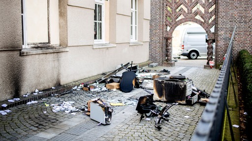 Verkohlte Möbelstücke liegen auf einem Gehweg vor dem Rathaus in der Innenstadt von Delmenhorst.