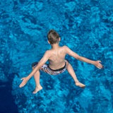 Ein Junge springt von einem Sprungturm in ein Schwimmbecken.