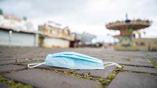 Eine Mund- und Nasenschutzmaske liegt auf der Bremer Bürgerweide.