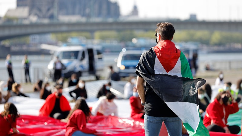 Auf einer pro-palästinensischen Demo entrolle Demonstranten eine große Palästina-Flagge.
