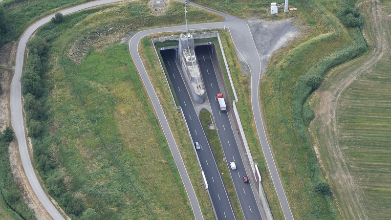Die Luftaufnahme zeigt wie ein LKW und Autos, bei Dedesdorf in den Wesertunnel fahren. 