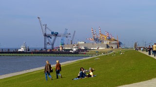 Menschen laufen über den Weserdeich in Bremerhaven.
