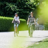 Ein Mann und eine Frau fahren mit ihren Rädern durch einen Park.