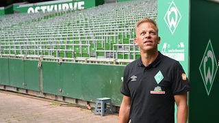Trainer Markus Anfang steht am Ausgang des Spielertunnels im leeren Weserstadion und schaut hoch auf die Ränge.