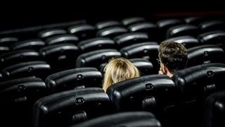 Zwei Besucher sitzen in einem Kinosaal.