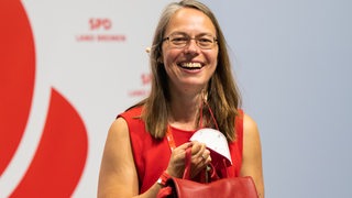 Sascha Karolin Aulepp (SPD), von ihrer Partei als neue Bildungssenatorin in Bremen nominiert, steht während des SPD-Parteitags Bremen lächelnd auf der Bühne.