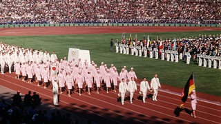 Frauen in pinken Uniformen laufen durch ein Stadion.