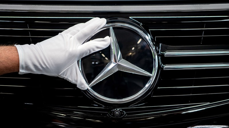 Ein Mitarbeiter von Mercedes-Benz montiert den Mercedes-Stern am Kühlergrill.