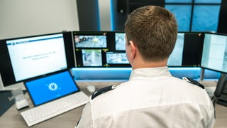 Ein Polizist steht an einem Computer.