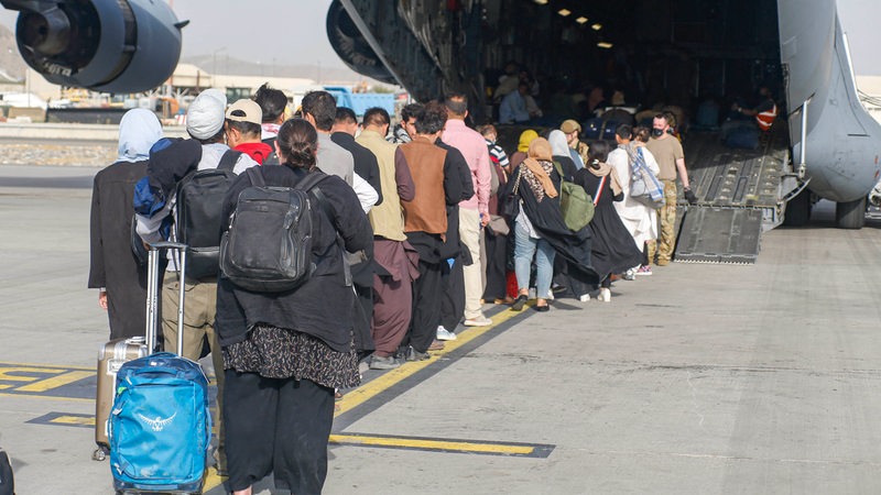 Menschen gehen am Flughafen Kabul in ein Flugzeug.