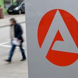 Ein Mann geht an einem Schild der Bundesagentur für Arbeit vorbei.