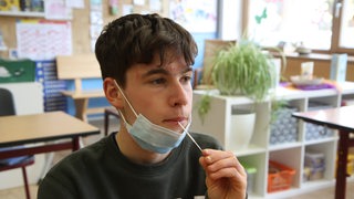 Ein Jugendlicher hat einen Lolli-Test im Mund