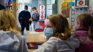 Schüler und Schülerinnen einer 4. Klasse arbeiten im Unterricht an der Grundschule Russee in Kiel zusammen in einem Klassenraum und tragen dabei einen Mund-Nasen-Schutz. 