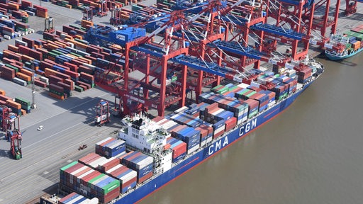 Eine Luftaufnahme zeigt ein Schiff und Container im Hafen.