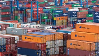 Viele Container stehen gestapelt in einem hafen.