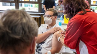 Mitarbeiter des Deutschen Roten Kreuz impfen Schüler.